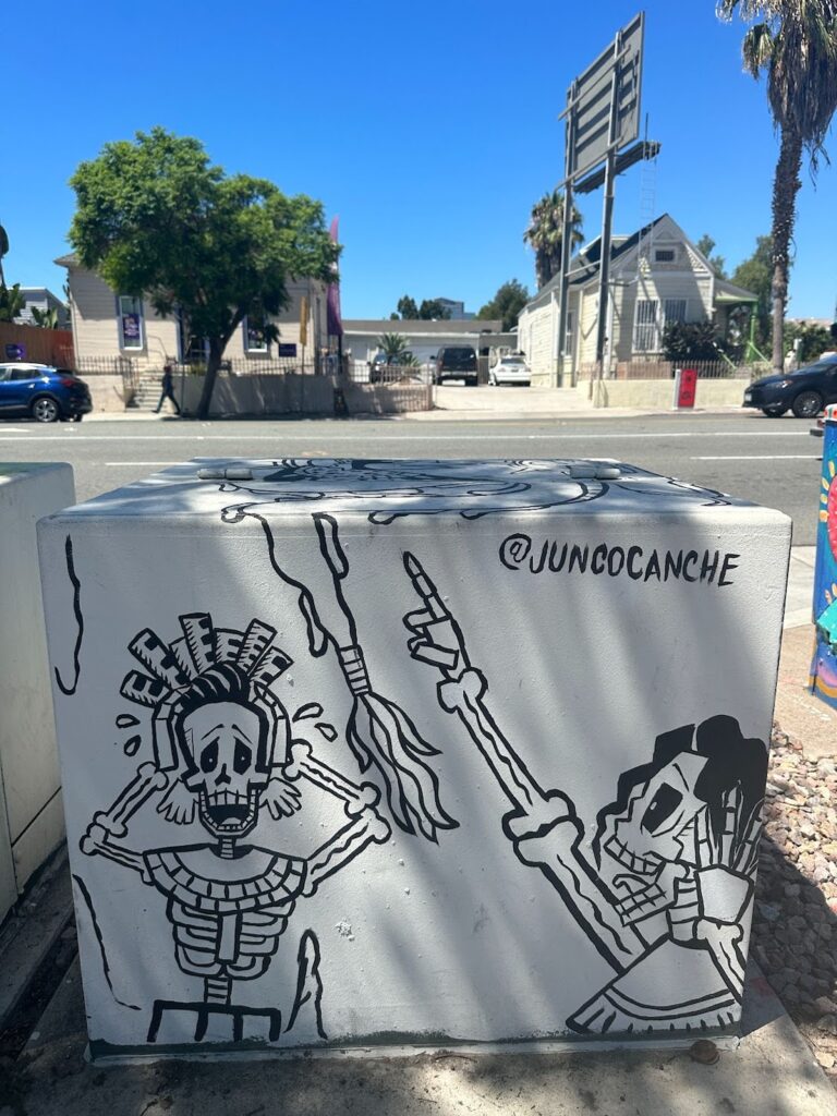 A Barrio Logan utility box mural with two skeleton figures in a state of panic