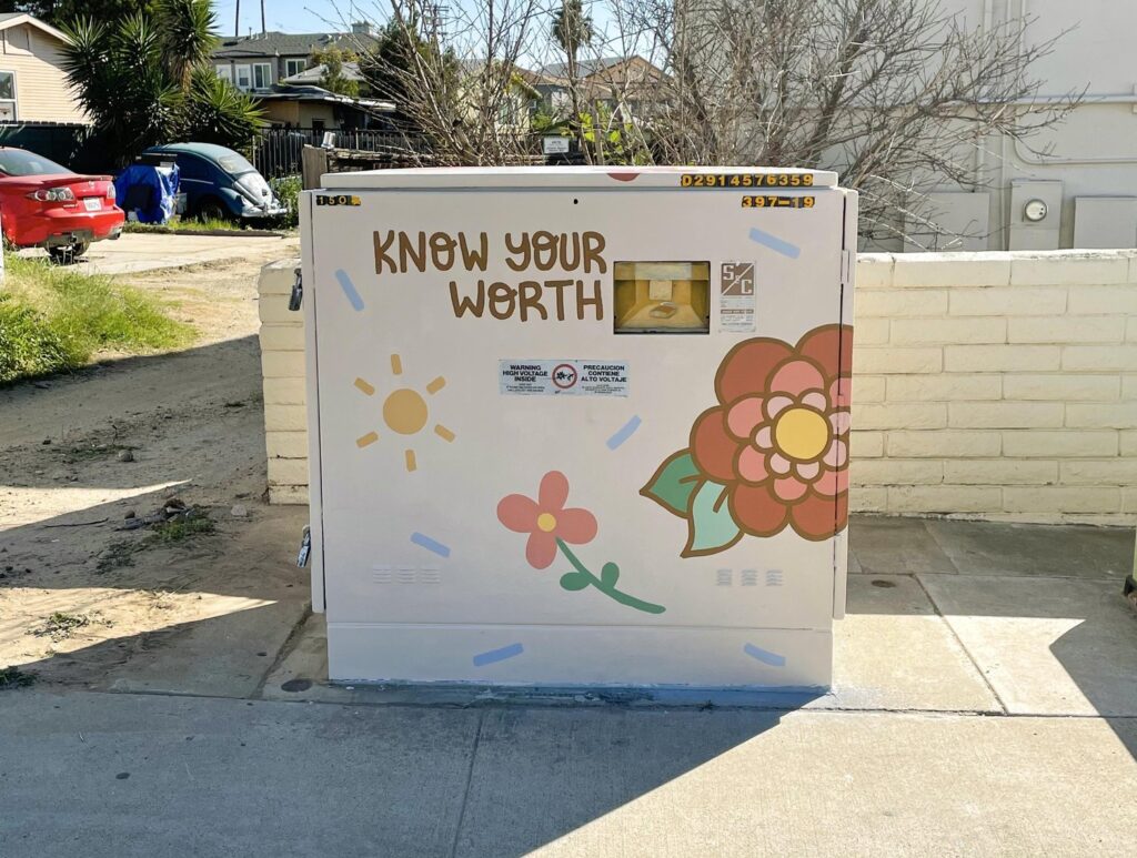A La Mesa utility box mural with flowers and a sun featuring the text "Know your worth"