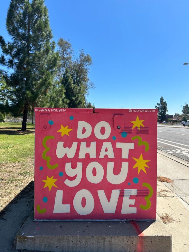 A Mira Mesa utility box mural that reads "Do What You Love" on a pink background with stars