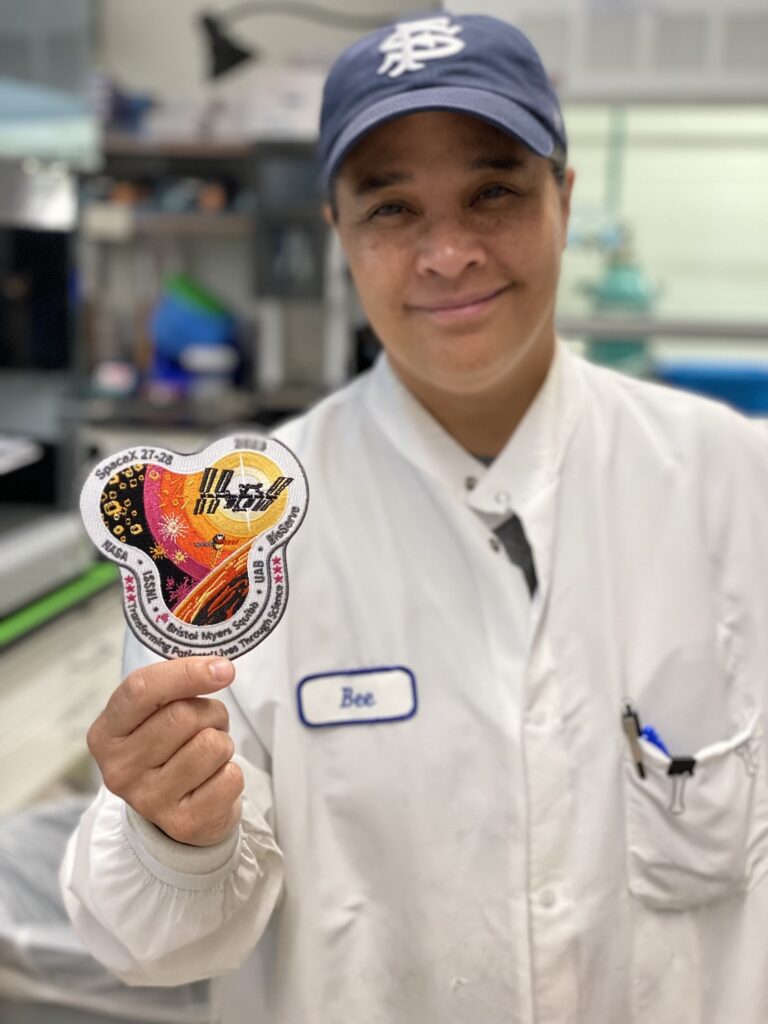 Barbra “Bee” Pagarigan a researcger at Bristol Myers Squibb in San Diego holding a SpaceX NASA patch